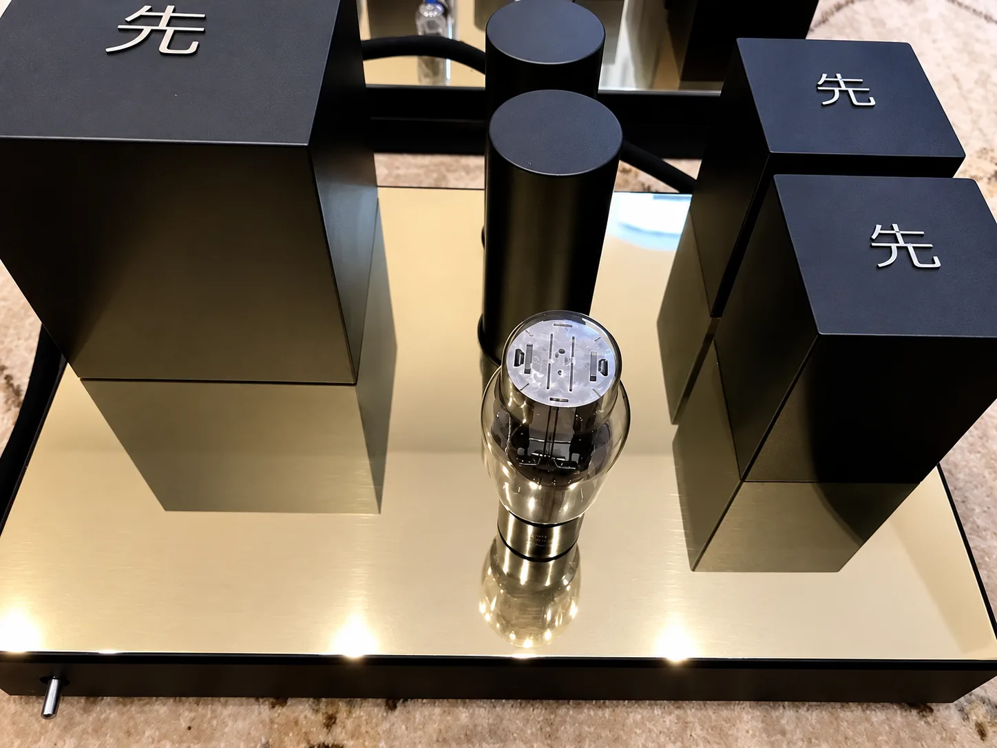 A close view of a Destination Audio amplifier chassis and its valve, standing on stone.