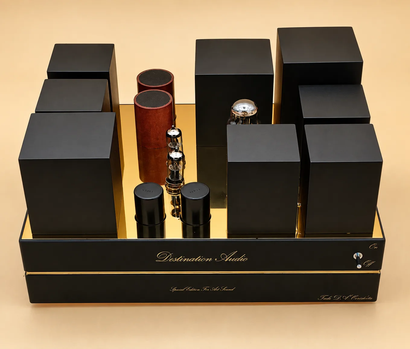 The Destination Audio tube digital-to-analogue converter on a warm cream ground, black blocks and copper cylinders set on a polished brass plate.