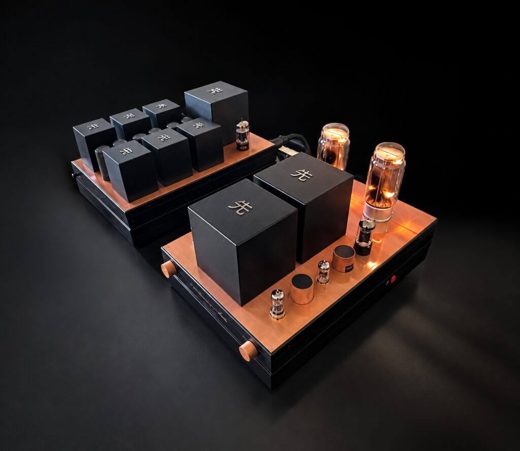 Two Destination Audio amplifier chassis in copper and black on a dark ground, their valves lit.