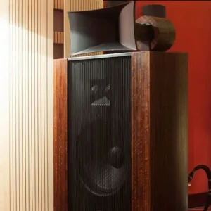 Tall, black textured Vista 3-Way Horn Speakers with reflective surfaces, displayed against a backdrop of red and wooden panels, resembling a field coil amplifier.