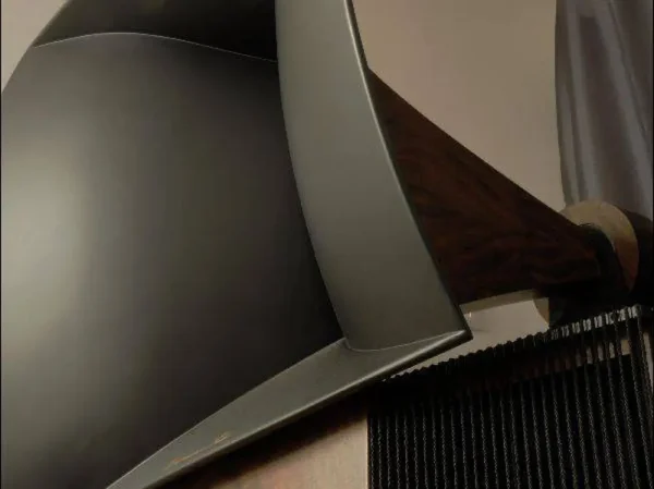 Close-up of a Vista 3-Way Horn Speakers with a sleek, curved metallic back and a wooden armrest, inspired by audiophile design aesthetics.