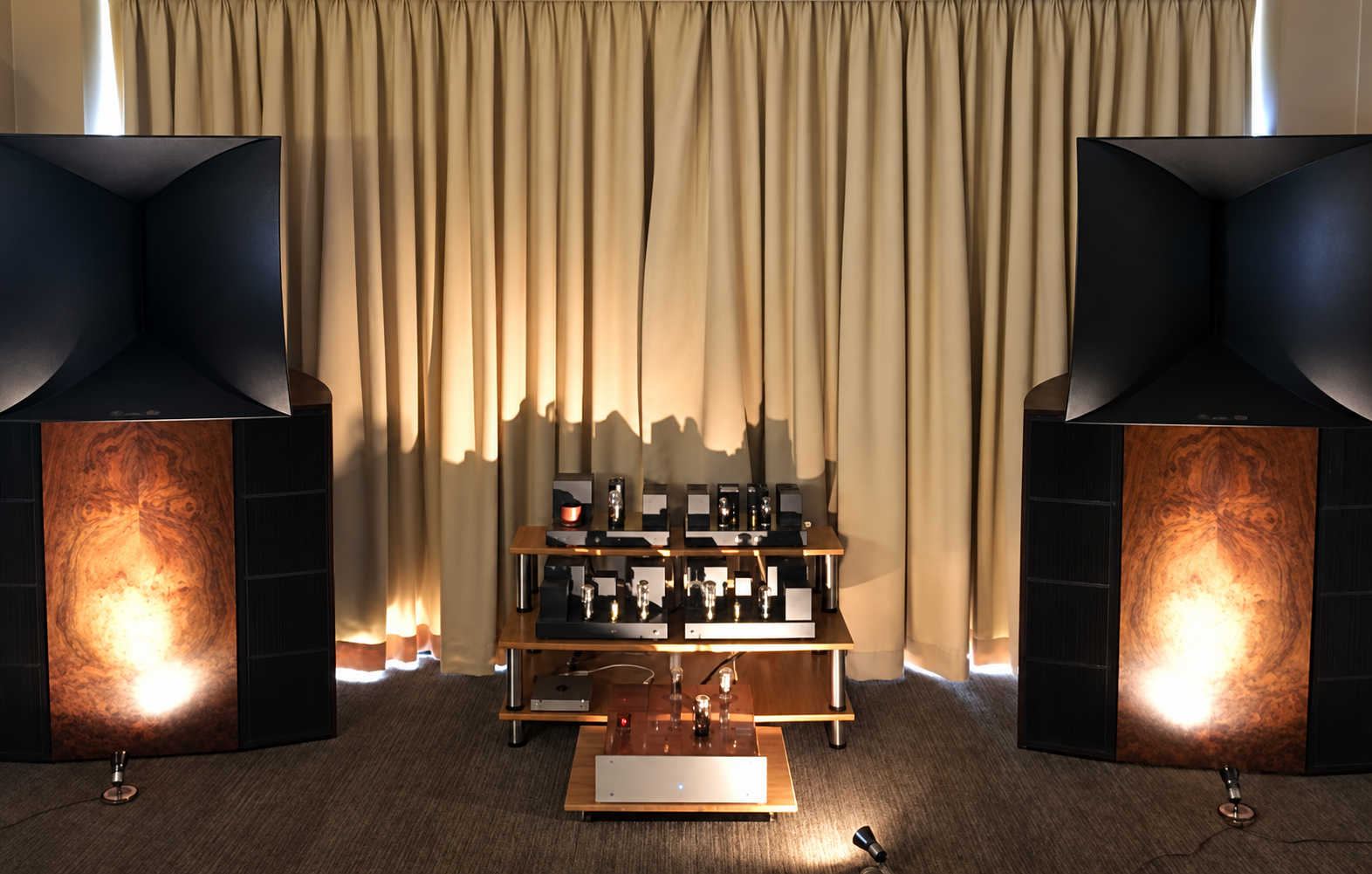 A pair of Destination Audio horn loudspeakers either side of a rack of valve electronics, the burl side panels lit from below.