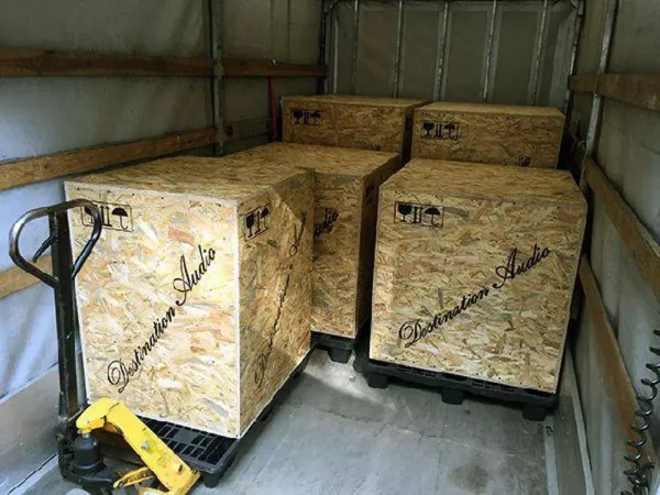 Three large wooden crates labeled "Vista 3-Way Horn Speakers" inside a shipping truck, arranged with a pallet jack nearby.