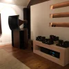 A home audio setup featuring Vista 3-Way Horn Speakers, vintage amplifiers on a wooden shelf, and wall-mounted acoustic panels in a dimly lit room.
