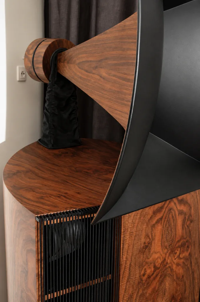 A walnut driver motor housing engraved Destination Audio, mounted on a black leather surround above a burl cabinet.