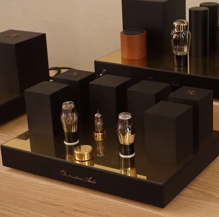 Destination Audio tube amplifier units with black transformer housings and brass-colored top plates on a wooden table
