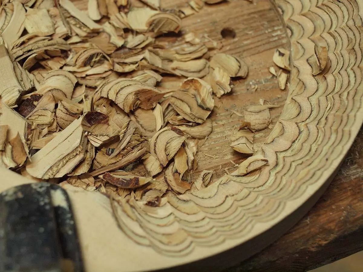 Wood shavings inside a round wooden part being carved by hand