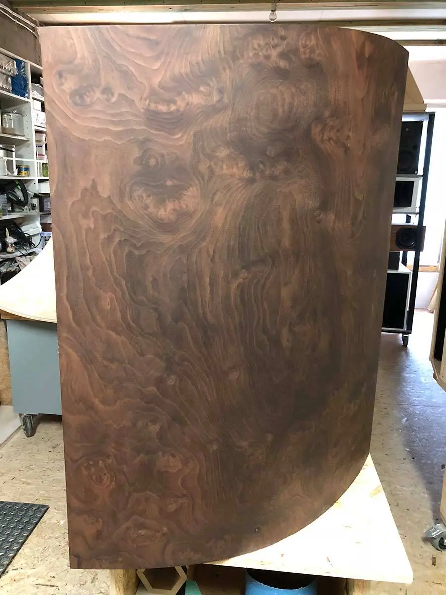 A tall curved cabinet panel covered in burl walnut veneer in the workshop