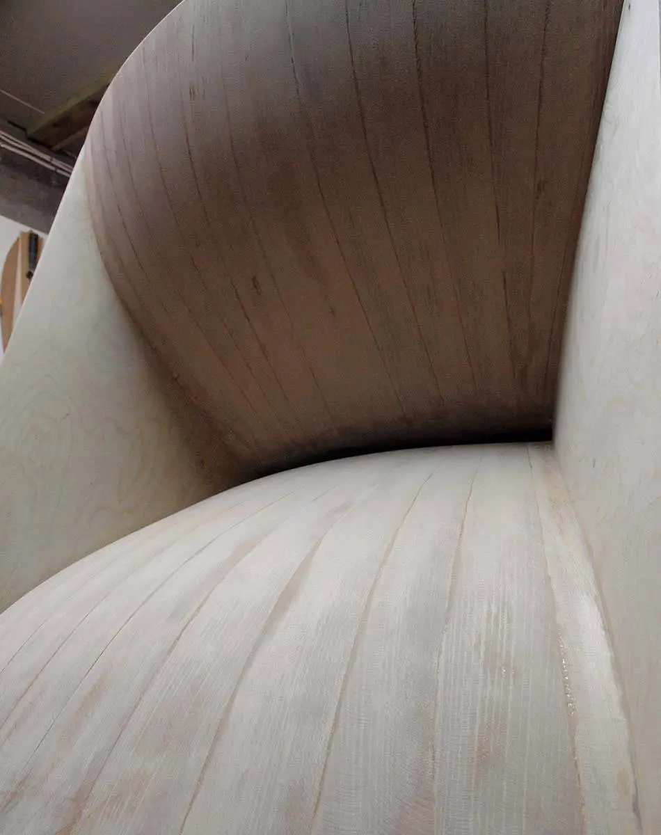 Inside of a curved wooden horn in the workshop, pale wood with dark veneer