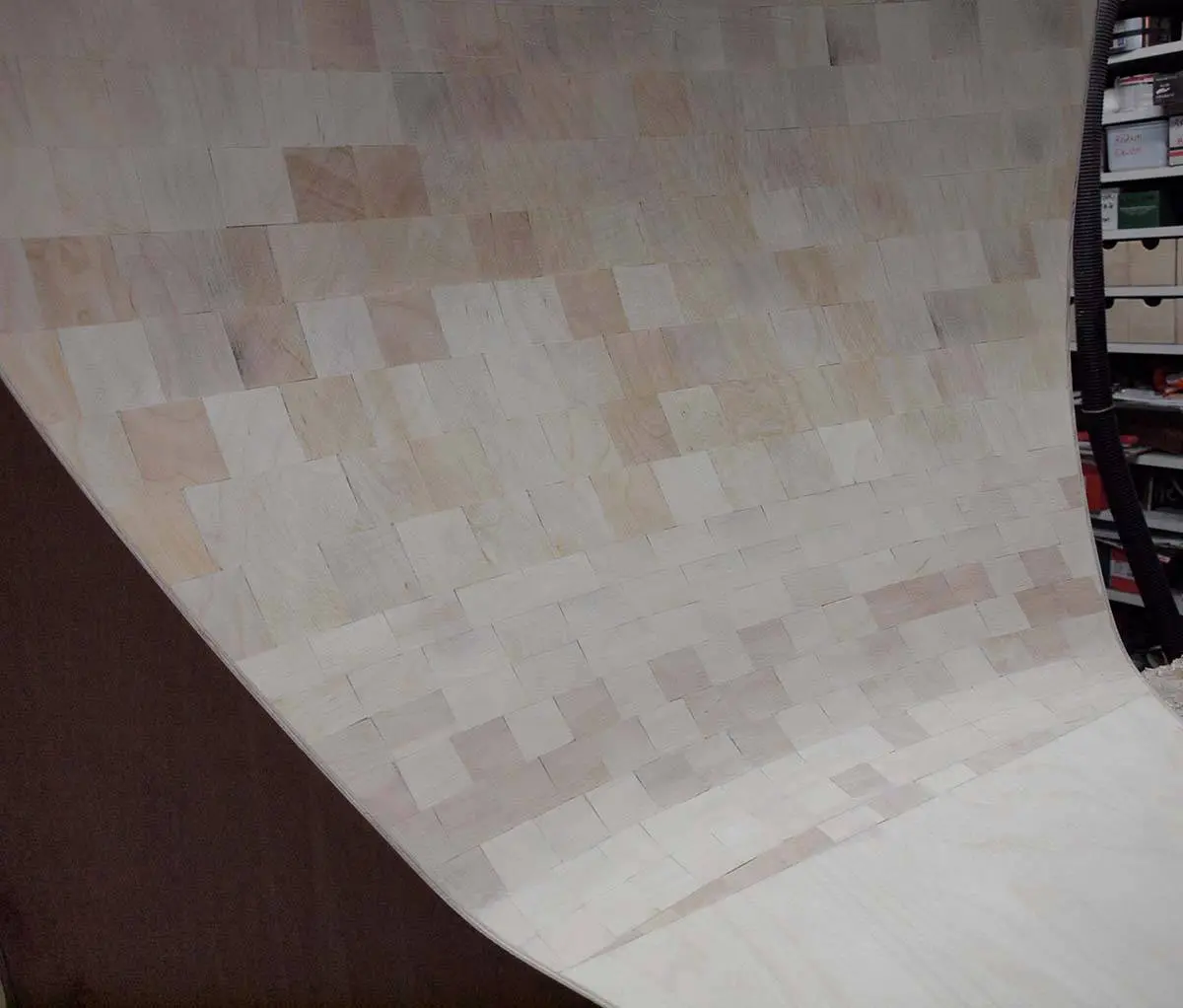 A large curved panel built from end-grain wood blocks in the workshop, part of a Vista horn