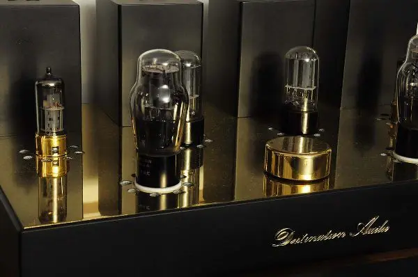 Close-up of vacuum tubes and a brass-colored knob on the polished top plate of a Destination Audio tube amplifier